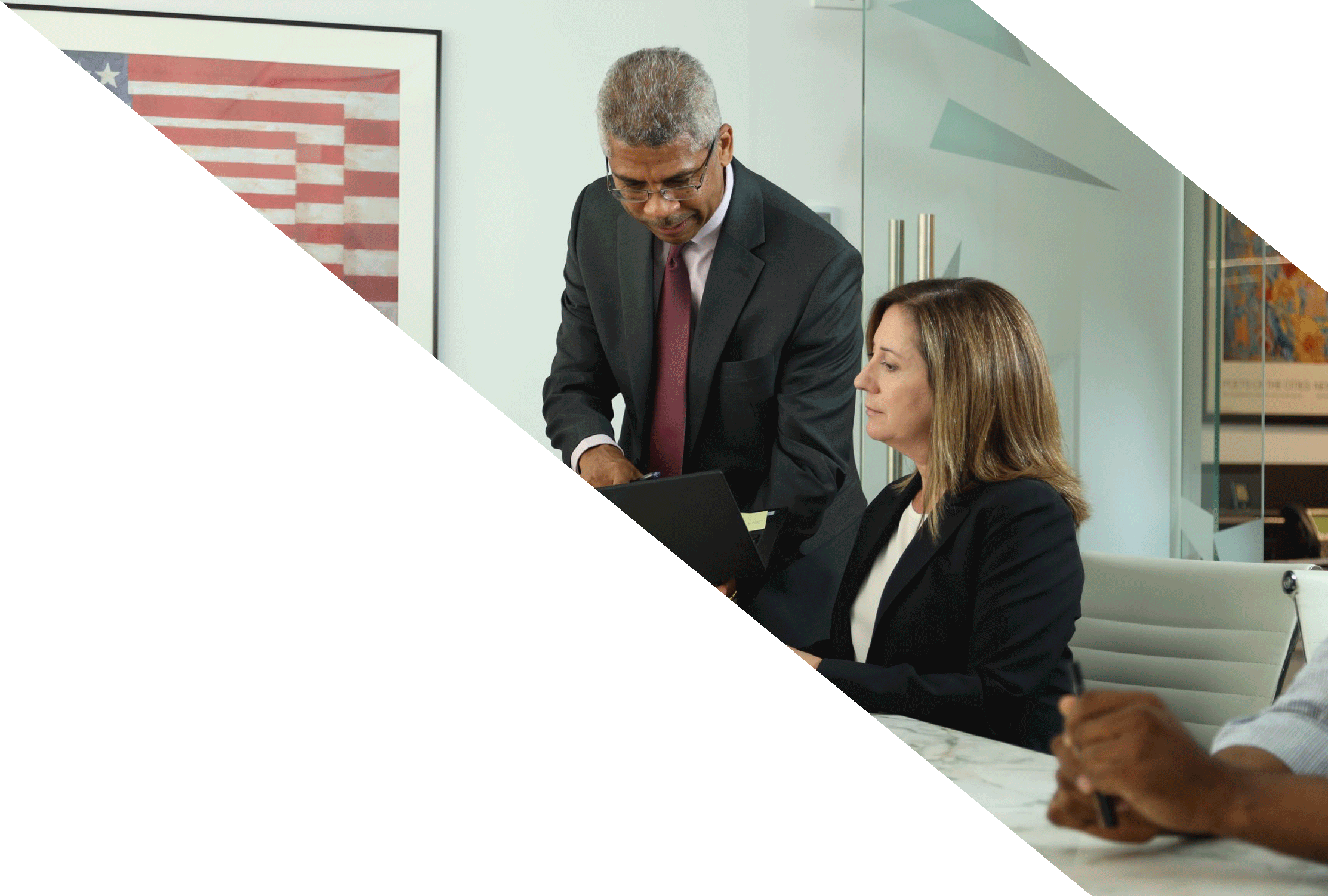 A man showing a coworker an item on a computer, potentially discussing topics such as Rule 144 and Restricted Securities.