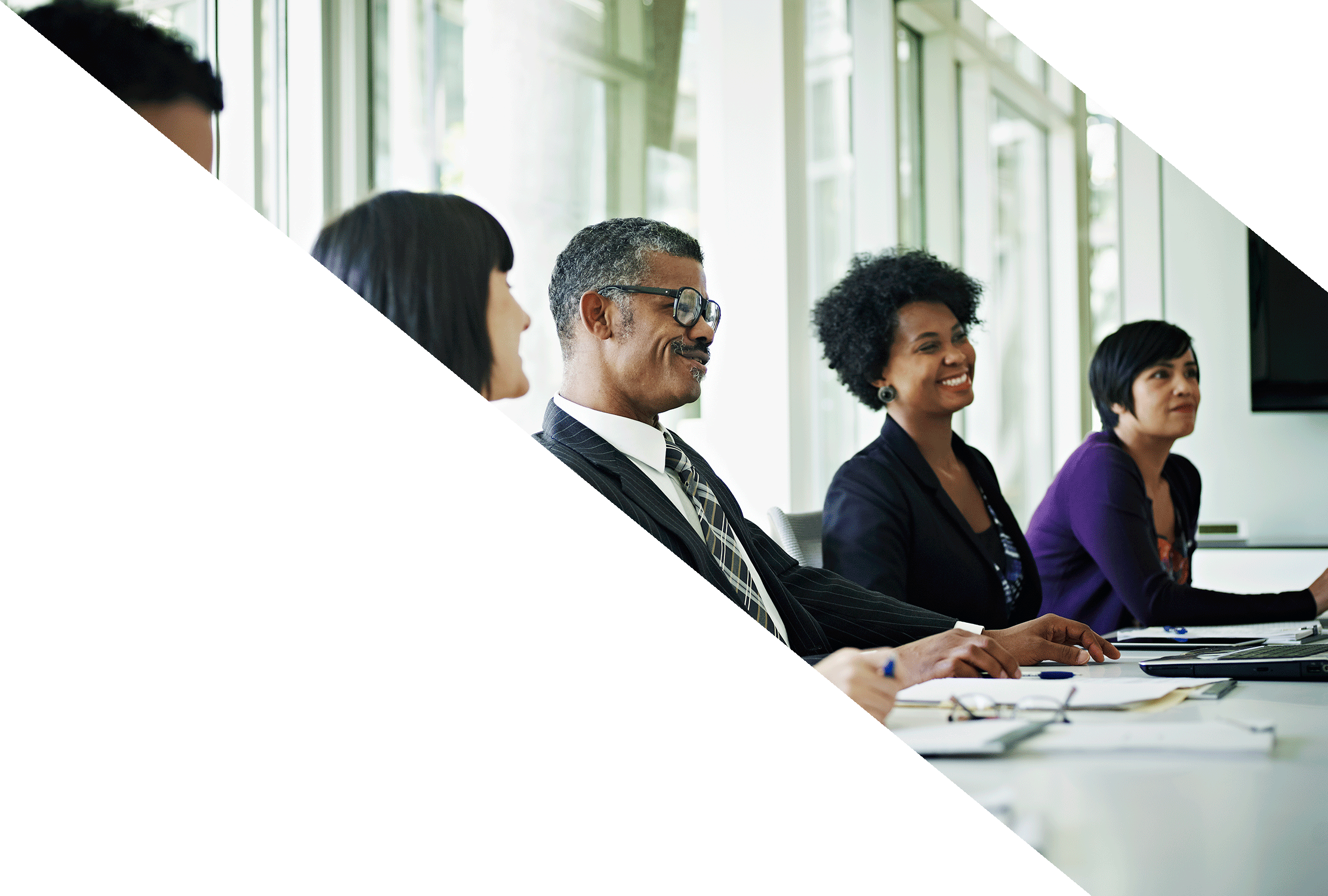 Four people seated on one side of a conference table, sharing laughter during shareholder and proxy meetings.