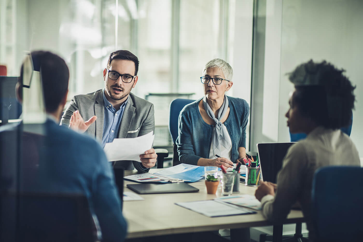 View of a conference room with four people engaged in discussion, likely about shareholders and proxy meetings.