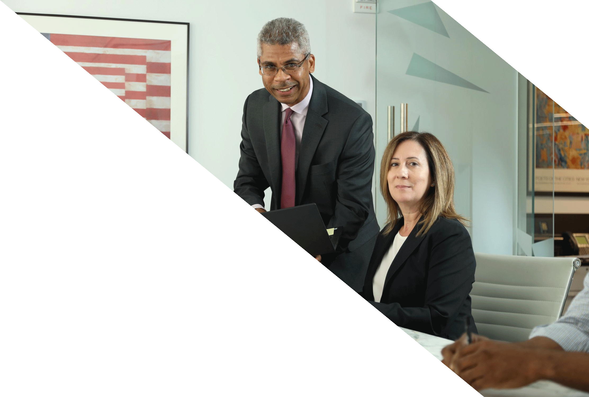 A man standing near a woman at a table, demonstrating financial solutions on a computer screen.