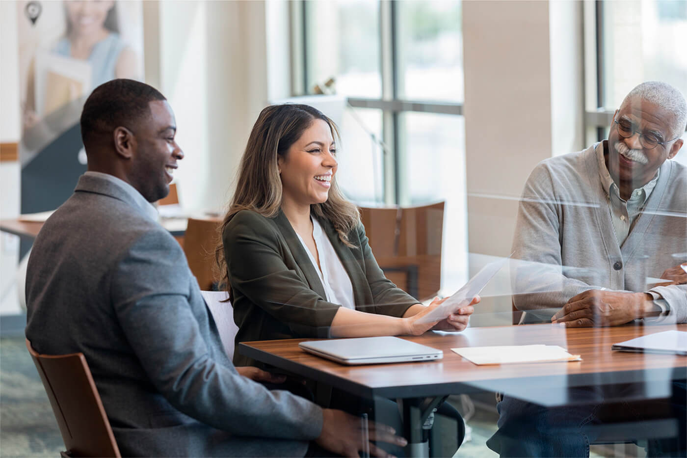 Three business people sitting at a conference table discussing financial solutions.