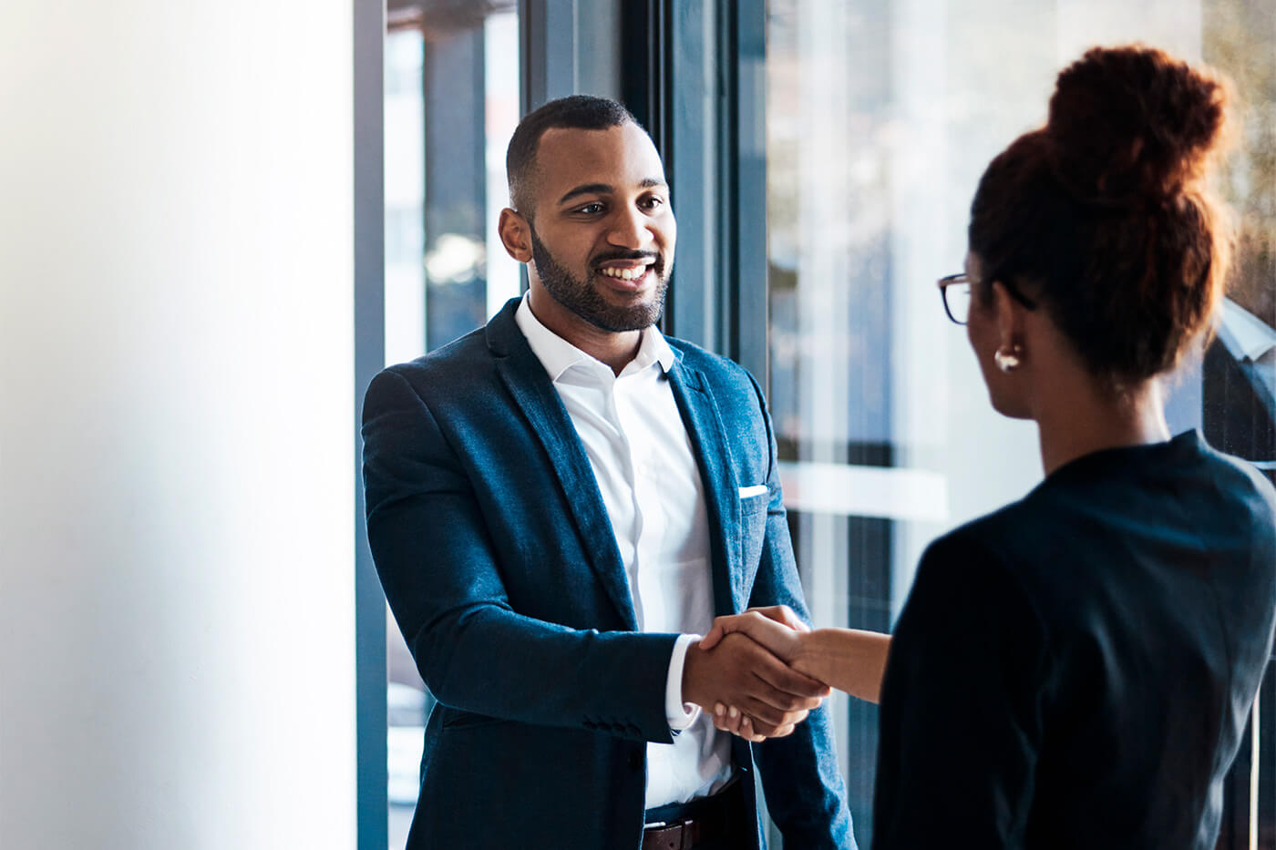 A man and woman shaking hands in a business setting, possibly signifying a partnership or agreement related to SPAC advisors and the IPO process.